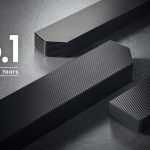 : "Samsung soundbar with sleek design and wireless subwoofer on a wooden table.